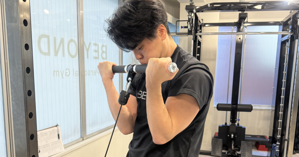 お客様がケーブルアームカールで腕を鍛えている